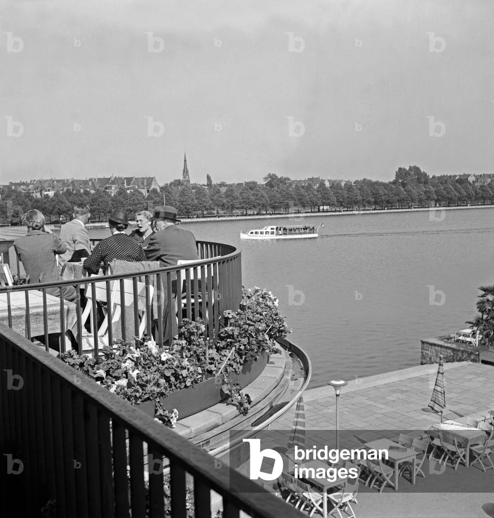 People at the outer terrace of the pavillon of the restaurant at the shore of Maschsee lake at Hanover, Germany 1930s (b/w photo)