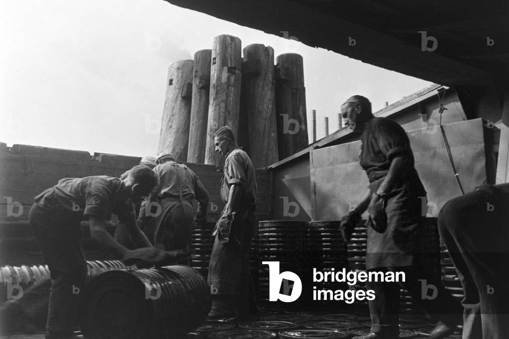 Warehousemen of the Rhenania Ossag Mineraloelwerke AG at Hamburg loading a ship with the bitumen product Mexphalt, Germany 1930s (b/w photo)