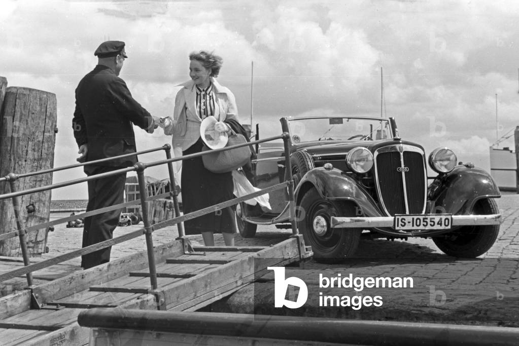 A woman and a sailor shaking hands by a gangway in front of an Audi convertible, Germany 1930s (b/w photo)