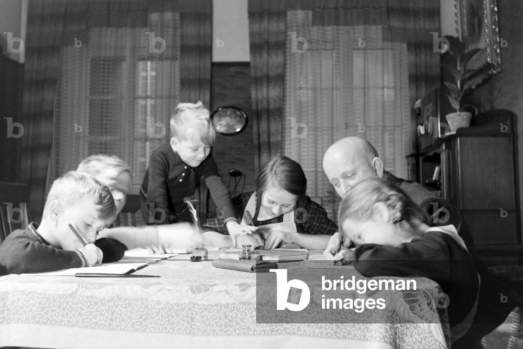 Members of a extended family doing the homework, Germany 1930s (b/w photo)