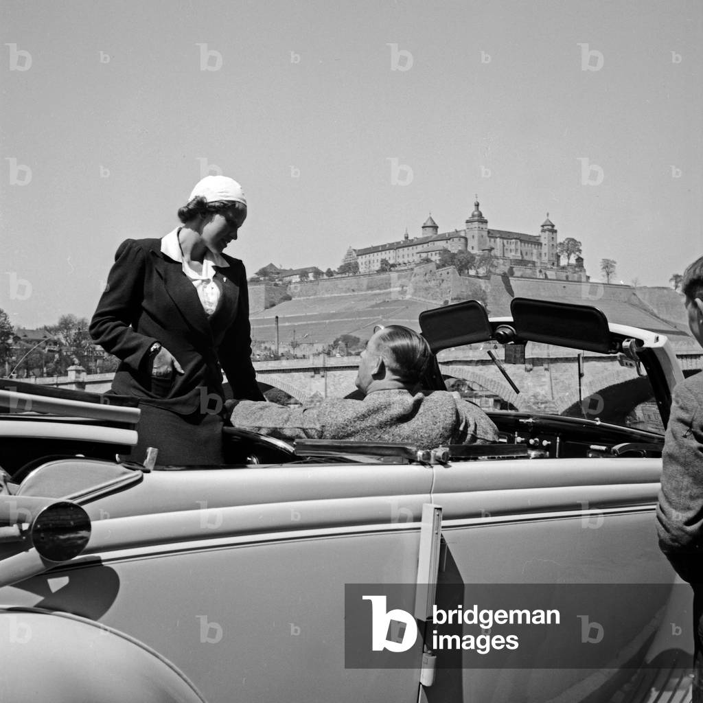 A family with their Ford V8 in front of Marienberg fortress at Wuerzburg, Germany 1930s (b/w photo)