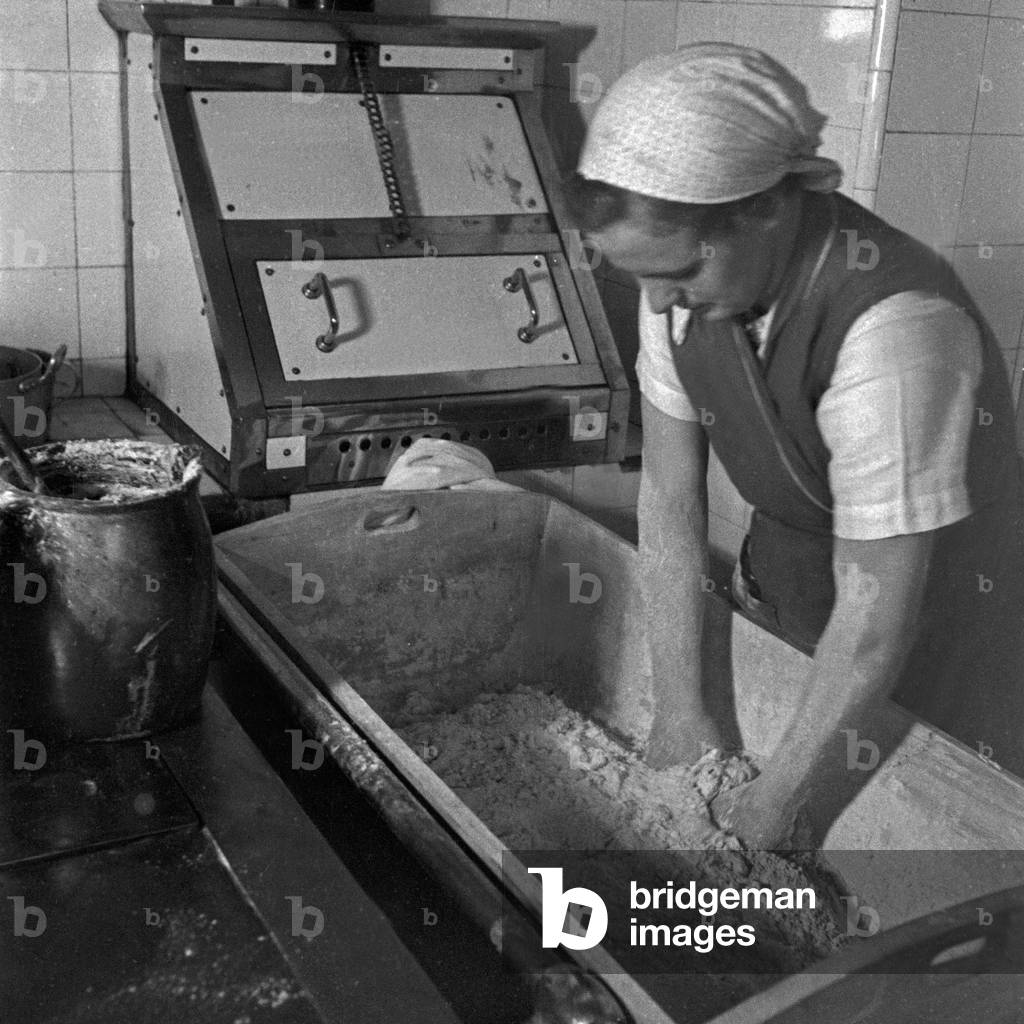 A woman mixing some dough at the female workforce group of Molkenberg, Germany 1930s (b/w photo)