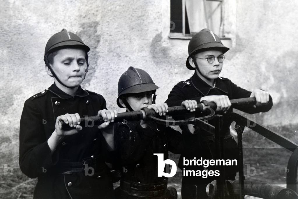 Boys of the junior firefighters using the hand pump during a training, Germany 1930s (b/w photo)