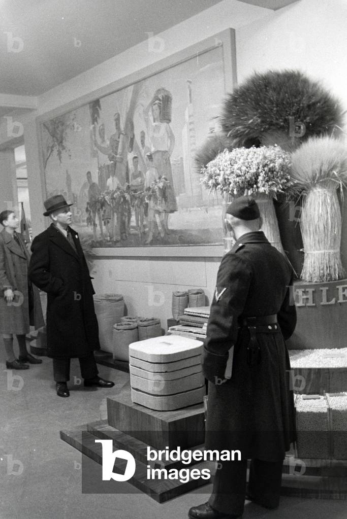 Visitors of the Leipziger Frühjahrsmesse in front of an information desk regarding the growing and cultivation of grain, Germany 1941 (b/w photo)