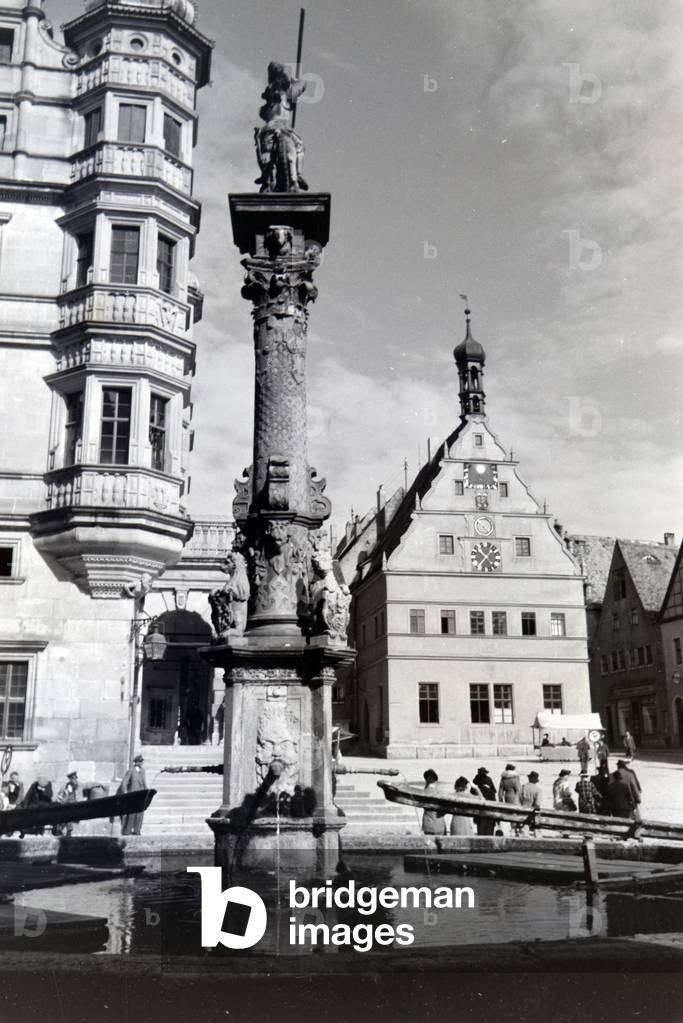 A fountain in front of the impressive townhall and the Ratstrinkstube in Rothenburg ob der Tauber, Germany 1930s (b/w photo)