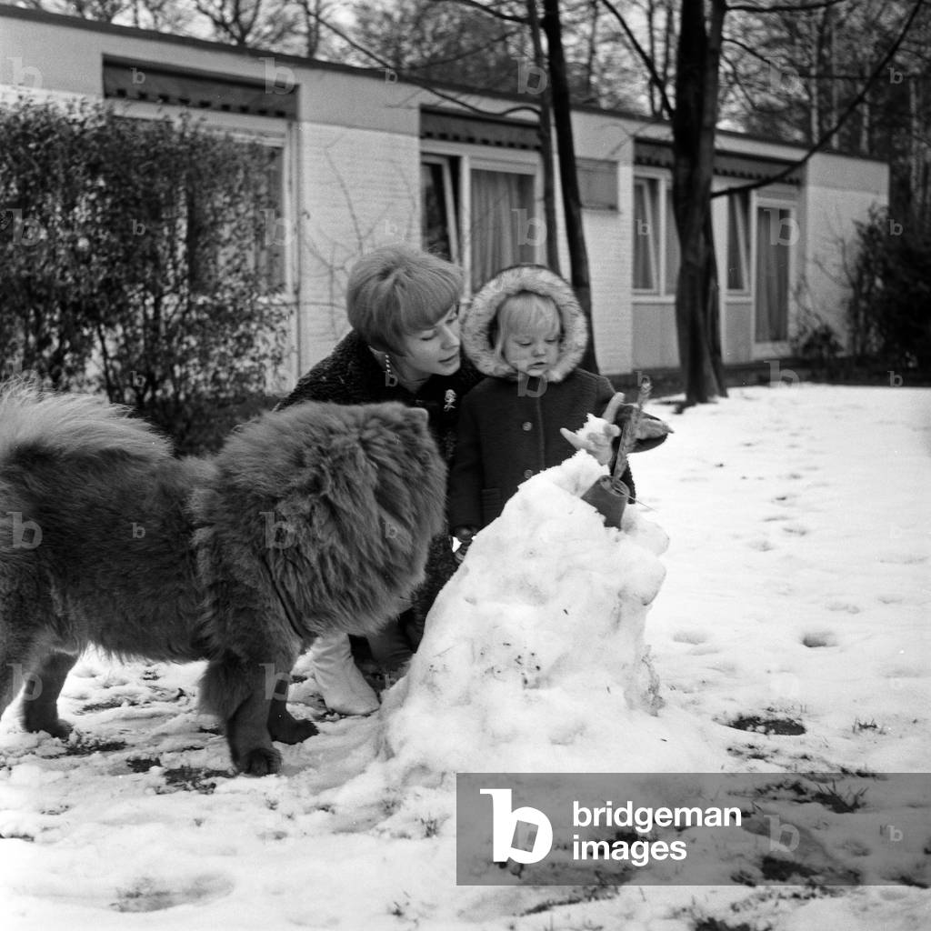 German actress Ingrid van Bergen playing with her daughter Carolin and their dog in the snow, Germany 1960s