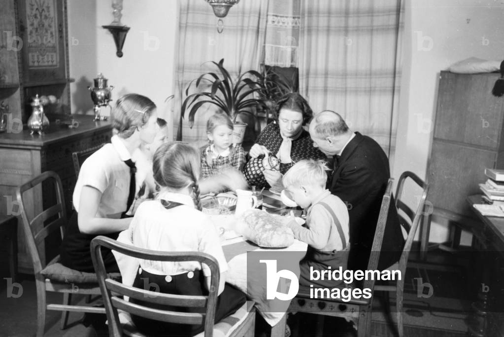 A mother and her five chidren having breakfast at the kitchen, Germany 1930s