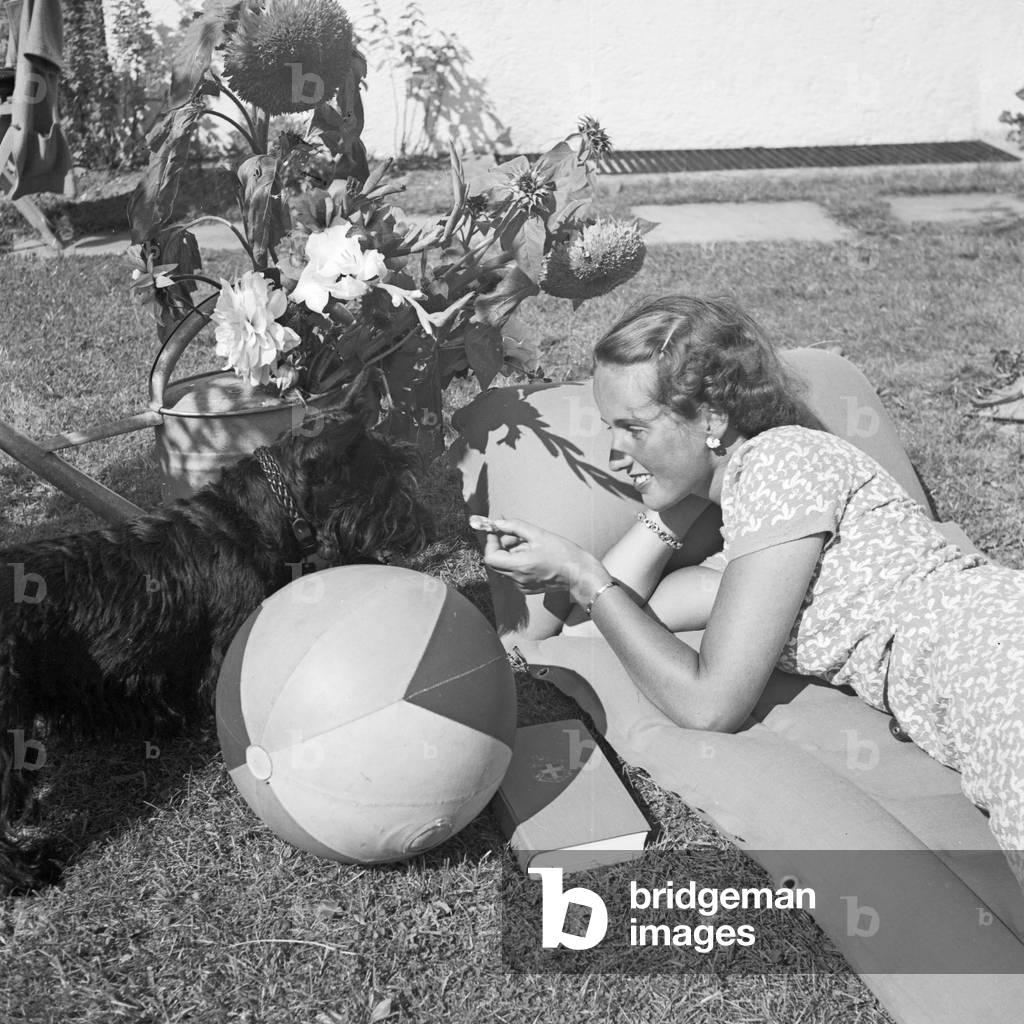 A young woman with her dog on a lawn, Germany 1930s (b/w photo)