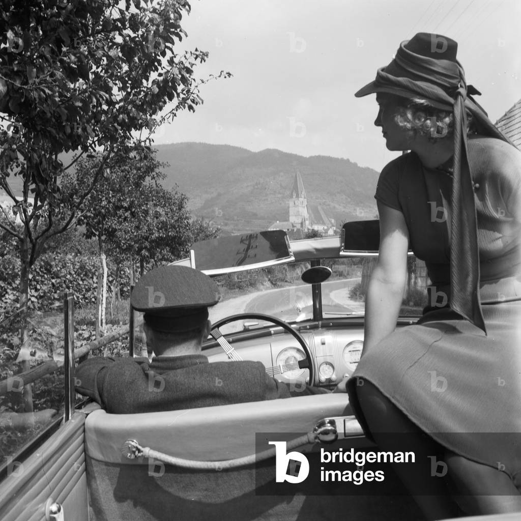 A driver transporting a young woman in an Opel model Admiral, Germany 1930s (b/w photo)