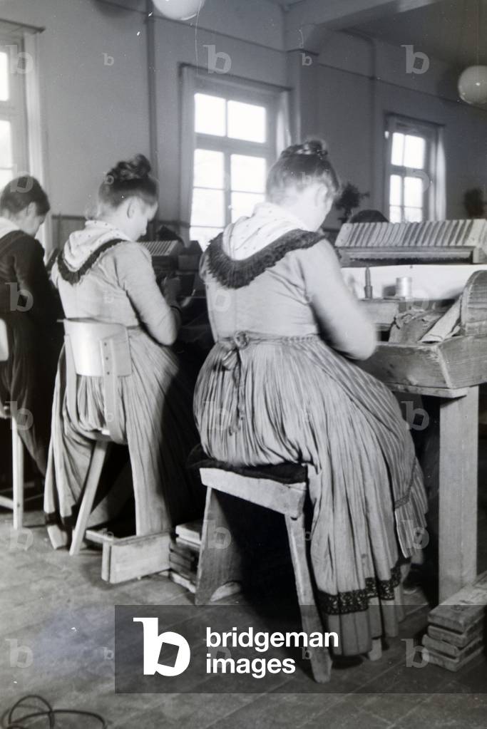 Female cigar rollers wearing a Marburg garb, costume at work in a cigar fabric near Marburg, Germany 1930s (b/w photo)