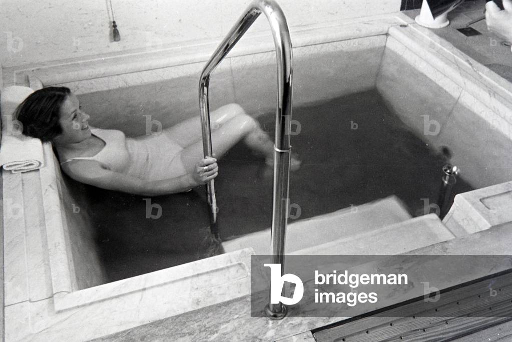A young woman visiting the hot water pool in the Caracalla Therme in Baden-Baden, Germany 1930s (b/w photo)