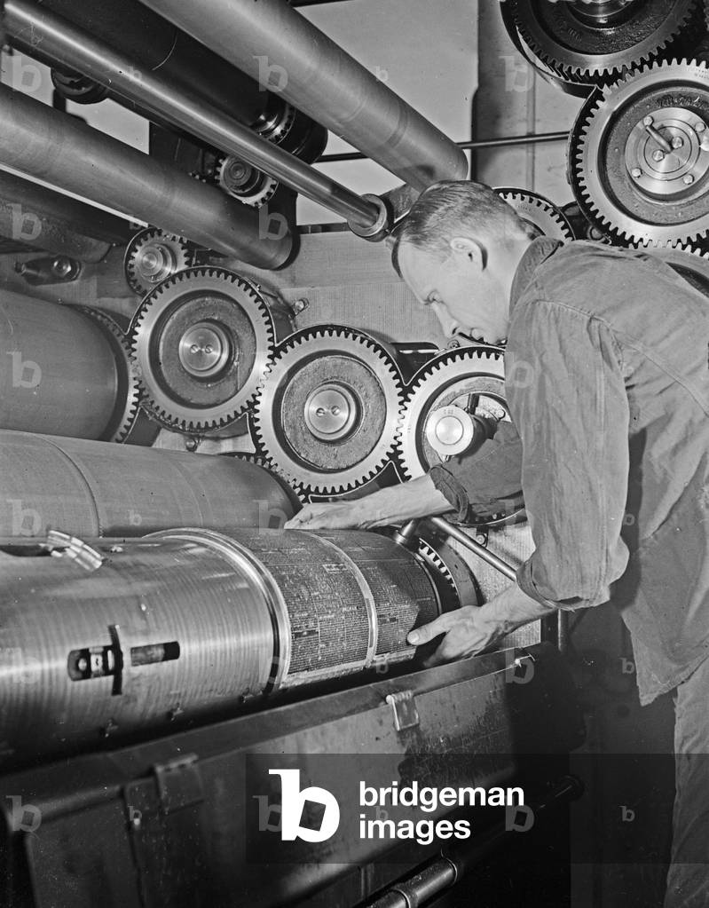 A man inserting a first print into a printing machine, Germany 1930s (b/w photo)