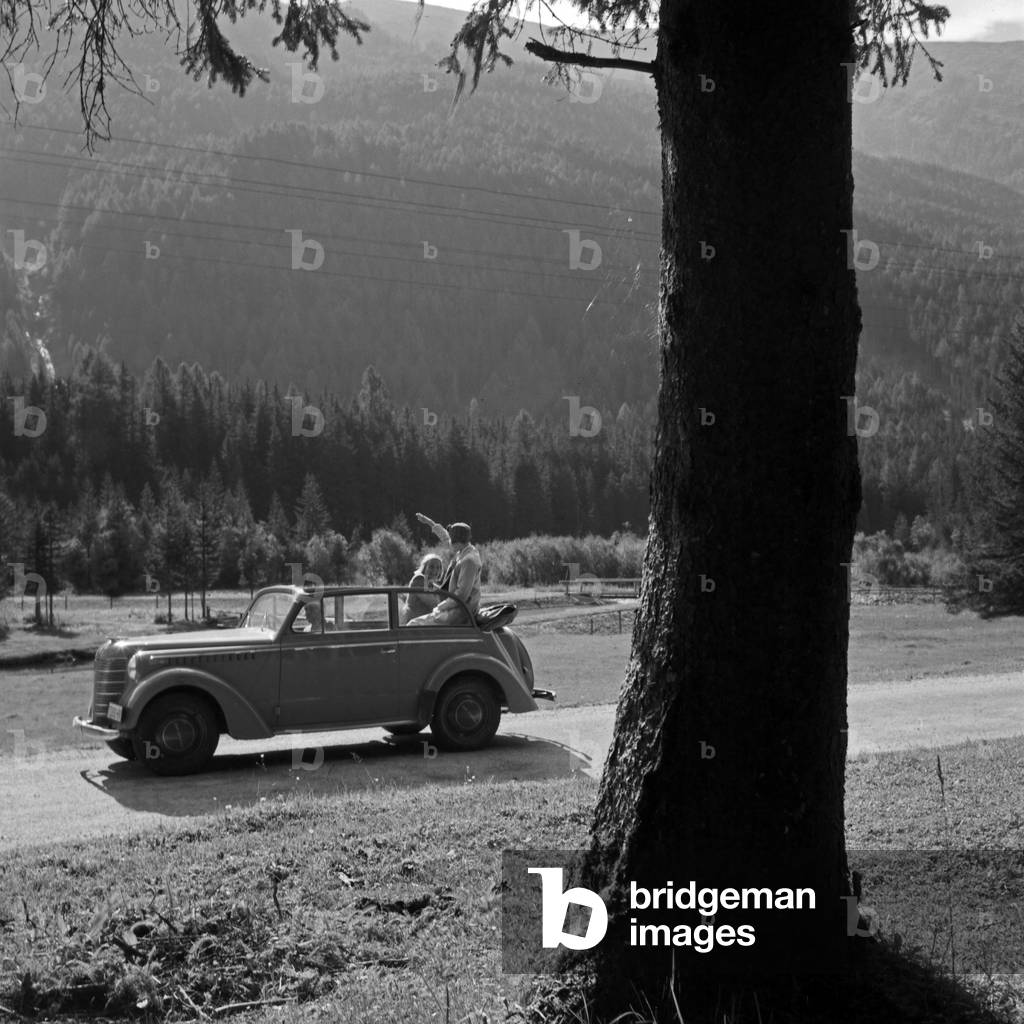 Three young people resting on their trip through Austria with Opel Olympia, 1930s, (b/w photo)