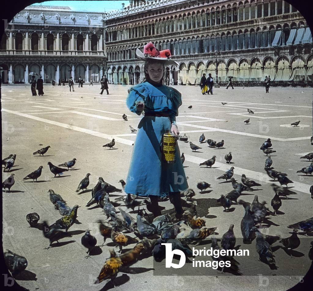 Italy, Venice, St. Mark's square, a girl feeds pigeons, image date: circa 1910. Carl Simon Archive