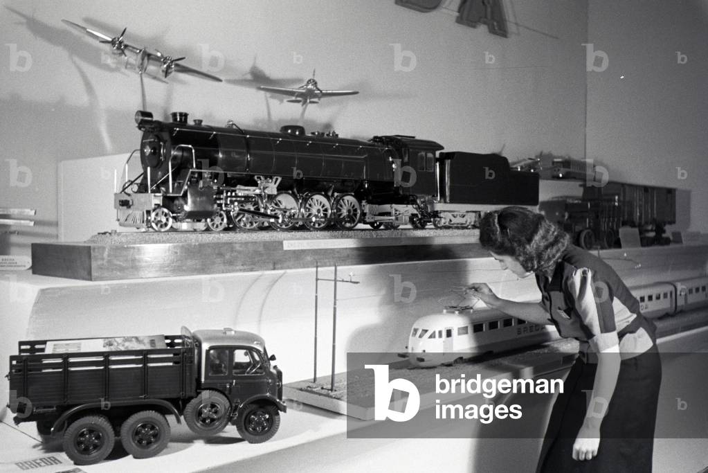 A visitor in front of a stand with models of the italian mechanical engineering corporation Breda on the Leipziger Frühjahrsmesse, Germany 1941 (b/w photo)