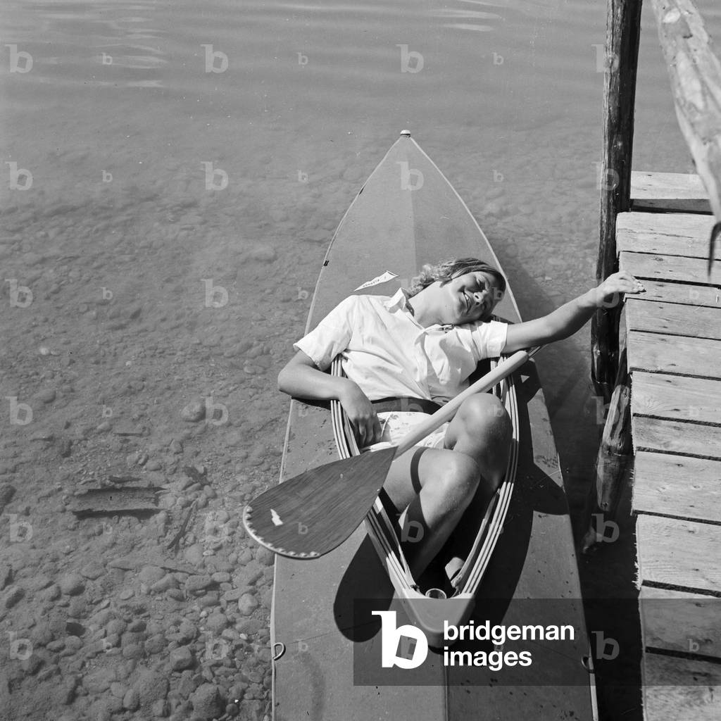 A young woman with her folding boat in the reed of a lake in the Wachau area, Germany 1930s (b/w photo)