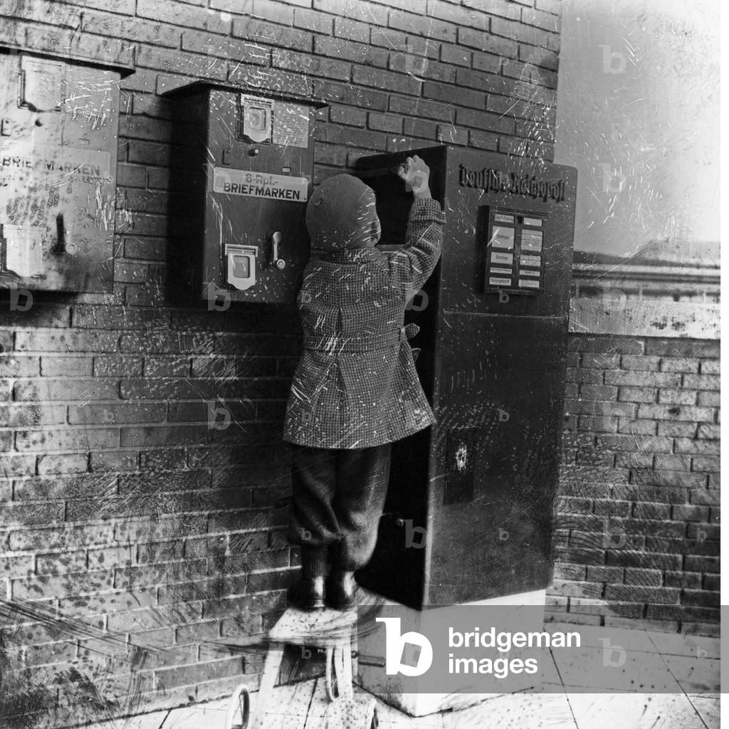 A little boy bringing a letter to the letter box, Germany 1920s (b/w photo)
