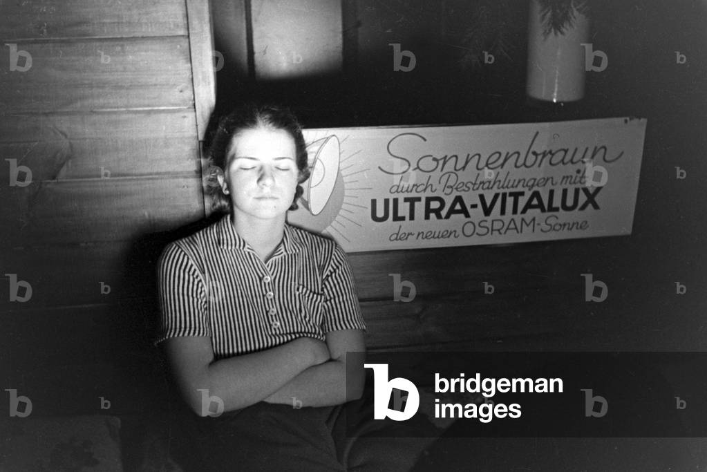 A young woman tanning with the new Ultra Vitalux sunlamp, Germany 1930s (b/w photo)