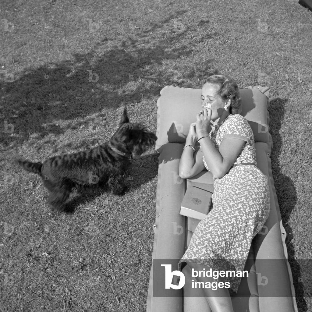 A young woman with her dog on a lawn, Germany 1930s (b/w photo)