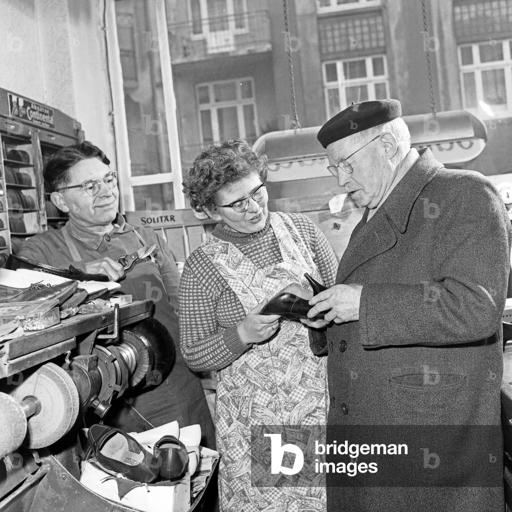 An elder man taking a pair of shoes from the shoemaker, Germany 1960s