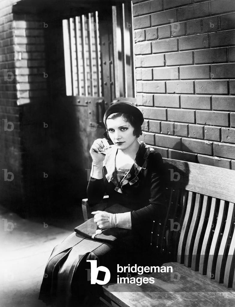 Young Woman Sitting N a Bench in Front of a Jail Cell