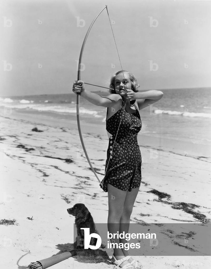 Woman Shooting Bow and Arrow on Beach