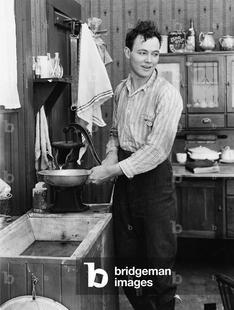 Man in a Kitchen Pumping Water