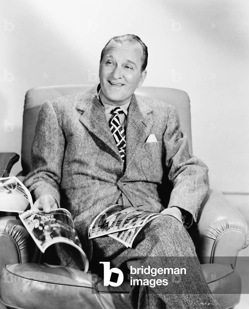 Man Sitting on an Armchair Reading a Magazine