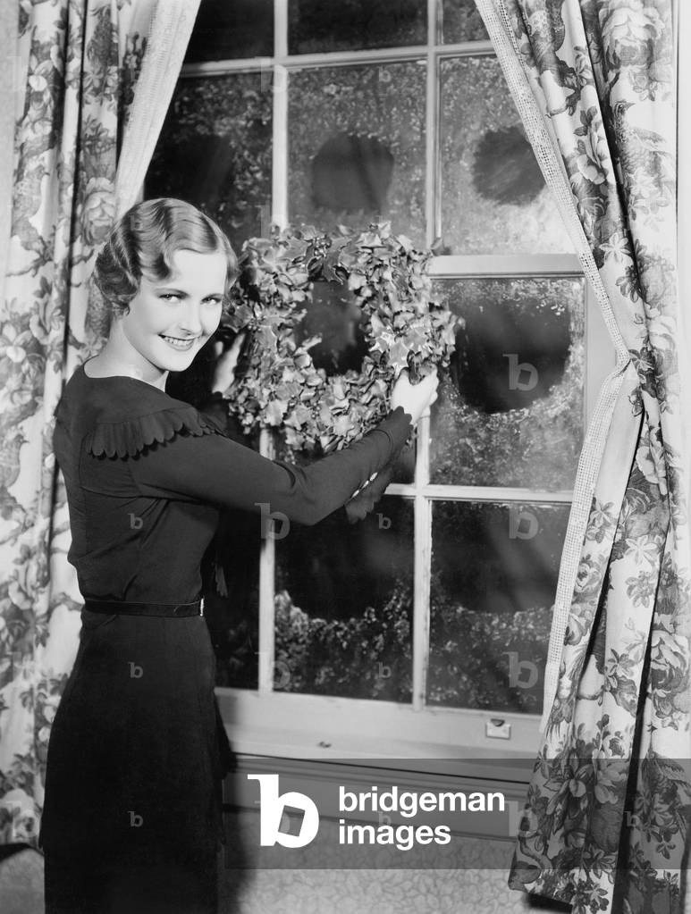 Woman Hanging up a Holiday Wreath