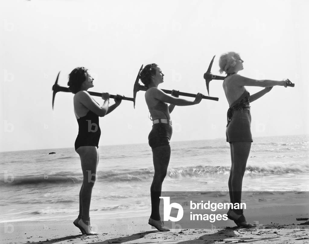 Three Women Posing with a Pick Ax on the Beach