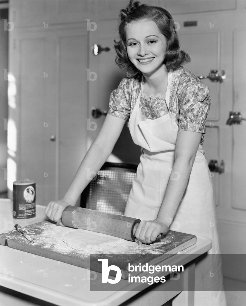 Young Woman Rolling Out Dough in the Kitchen