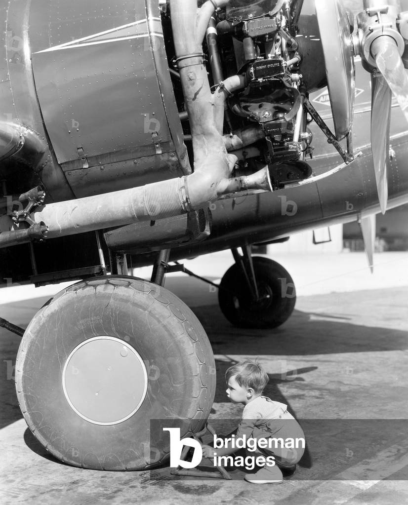 Little Boy Trying to Fix an Airplane Wheel