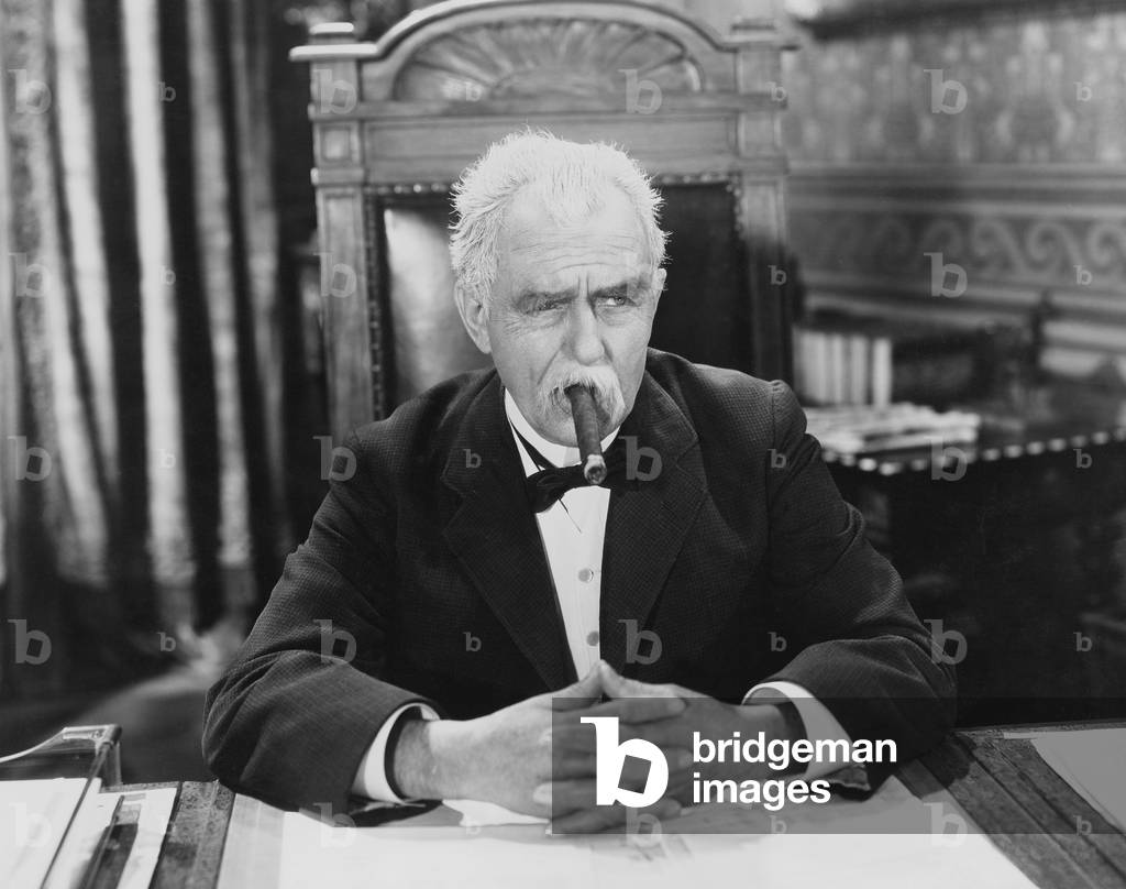 Businessman Smoking Cigar at Desk