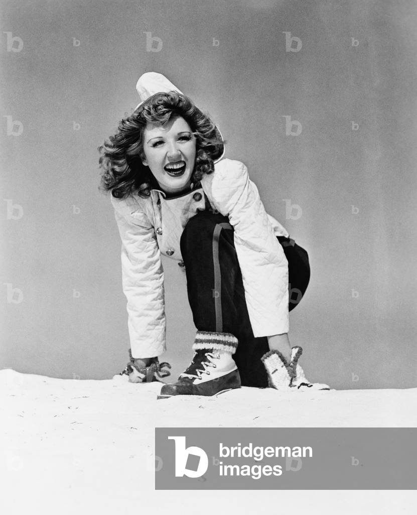 Young Woman Kneeling in Snow and Smiling