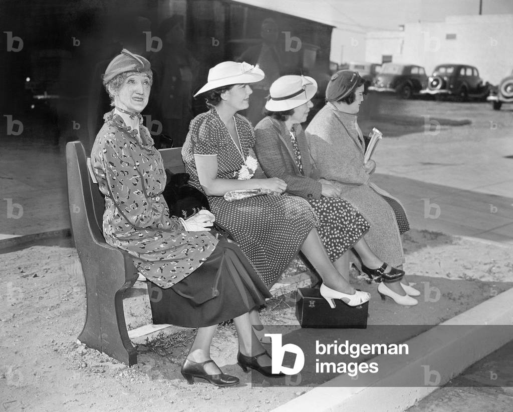 Four Women Sitting on a Bench Waiting for the Bus
