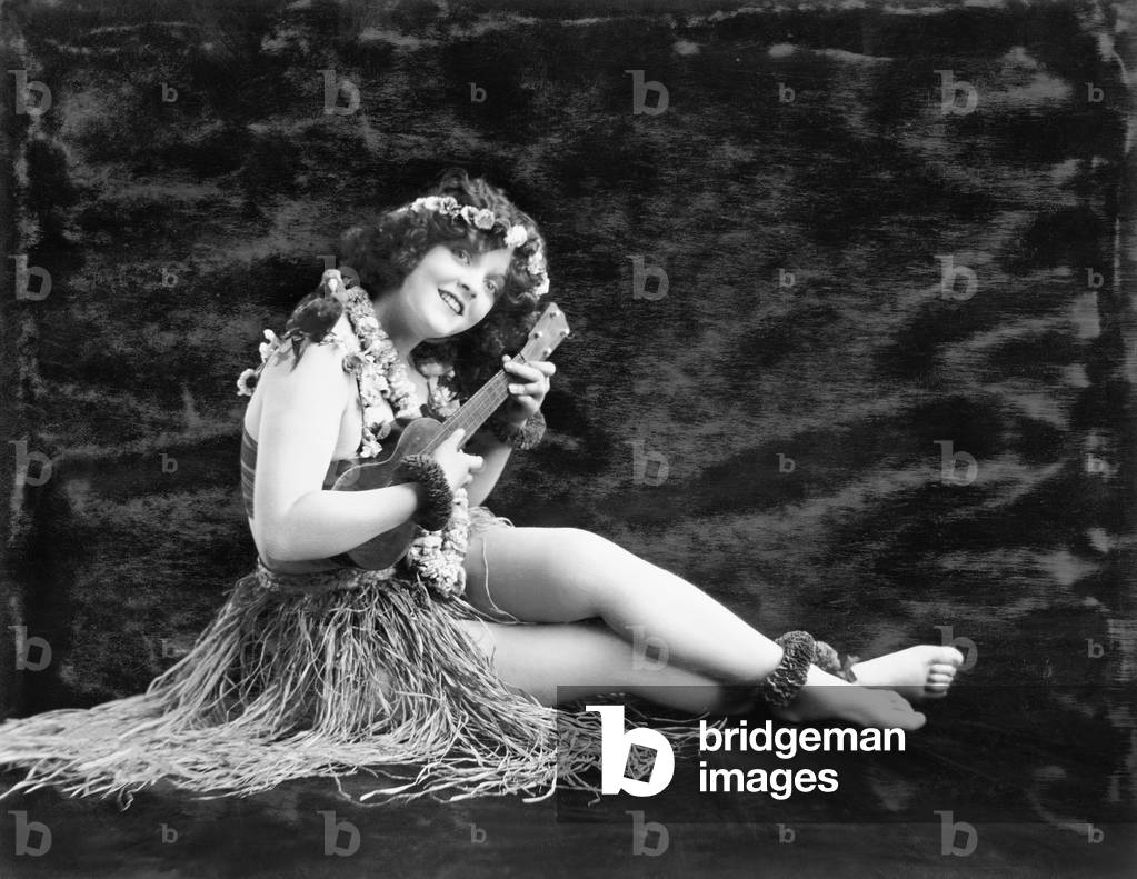 Young Woman Playing Guitar in a Hawaiian Grass Skirt
