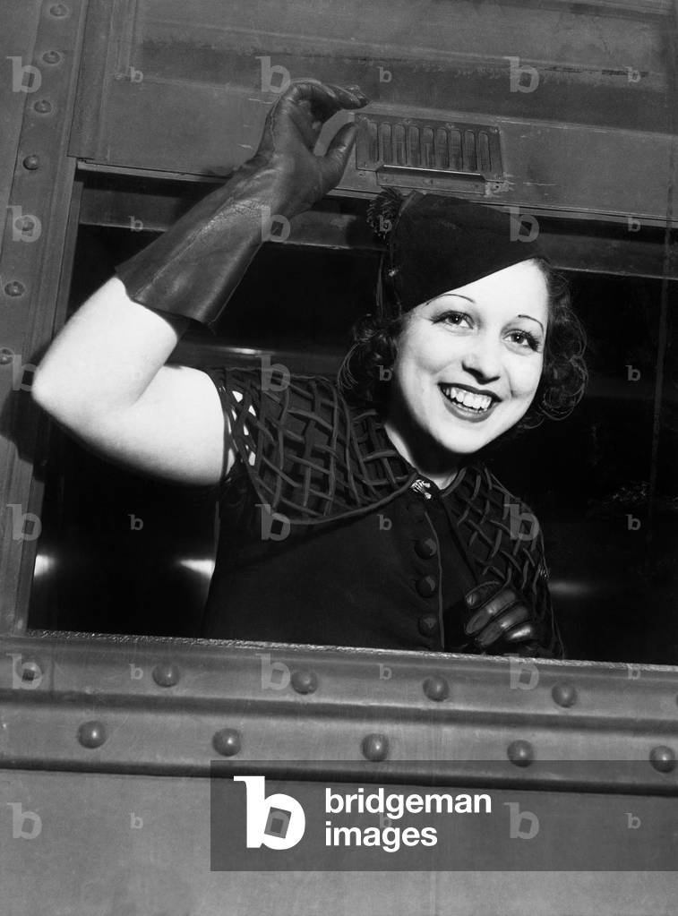 Low Angle View of a Young Woman Looking Through the Window of a Train and Smiling