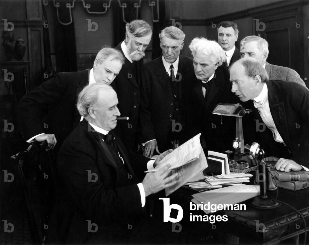 Men hovering around desk in anticipation of news