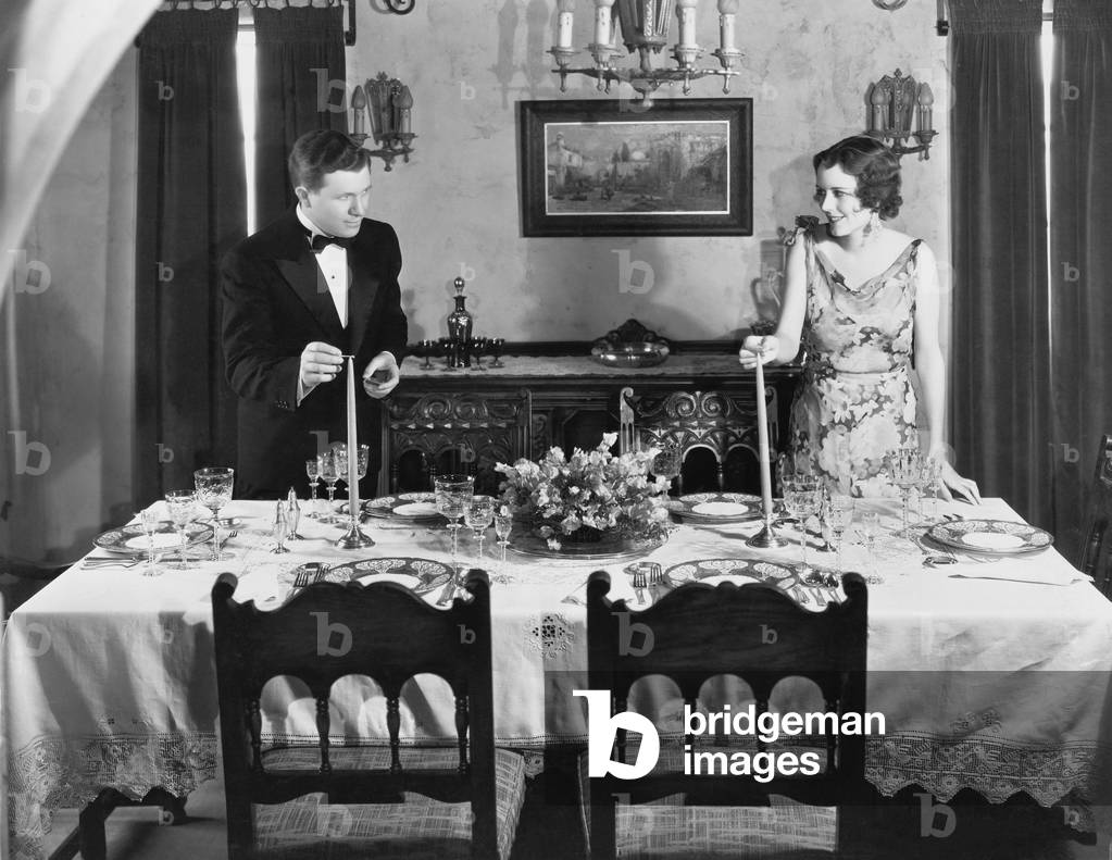 Couple Lighting Candles on Table Set for Dinner