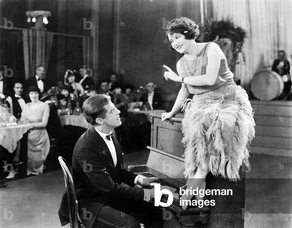 Young Woman Sitting on Top a the Piano and Talking with the Pianist