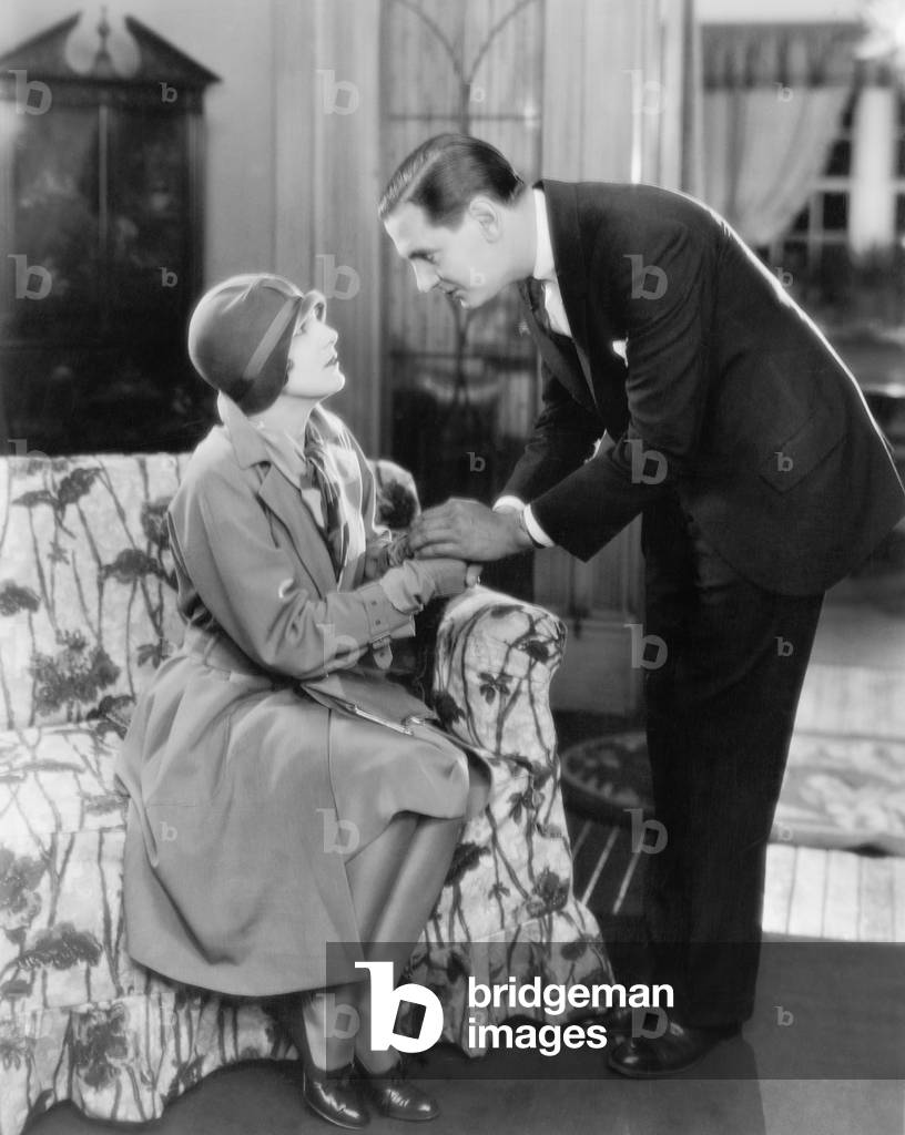 Man Bending Over a Woman Sitting on a Sofa