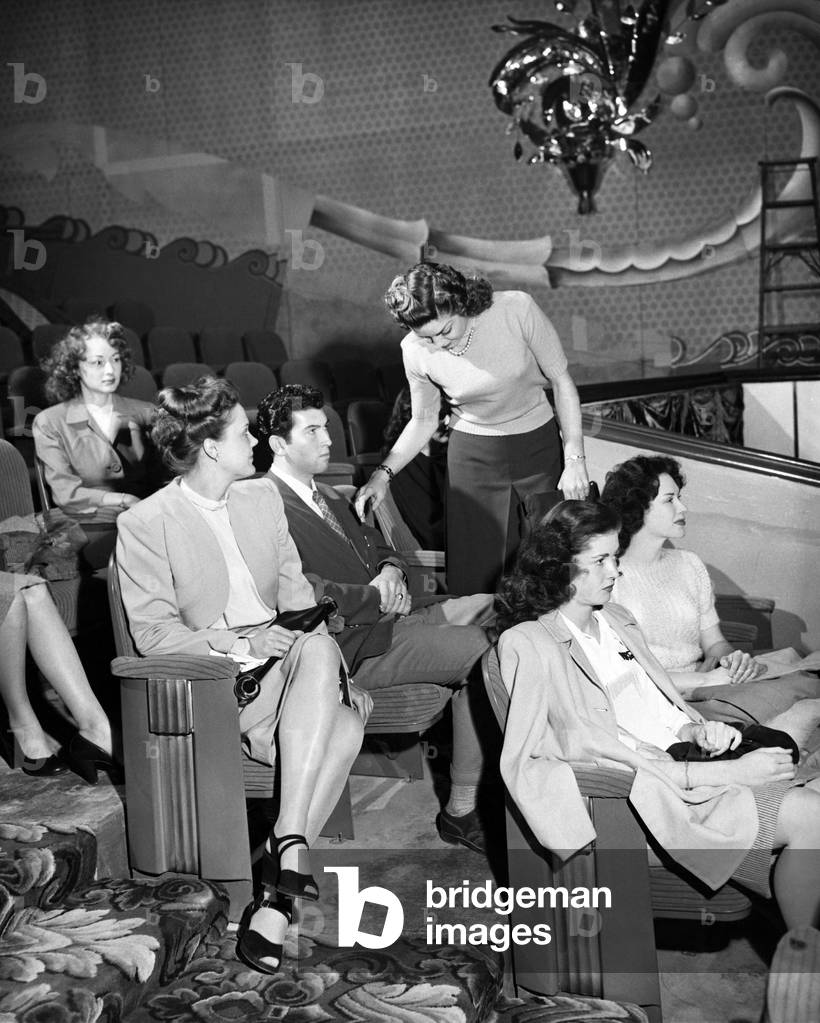 Woman Leaving Row of Audience in Theater