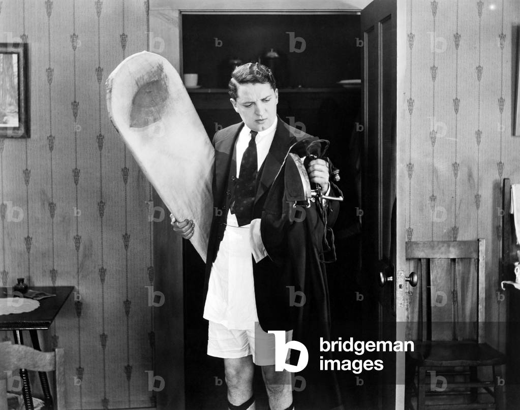 Man in boxer shorts holding iron and ironing board