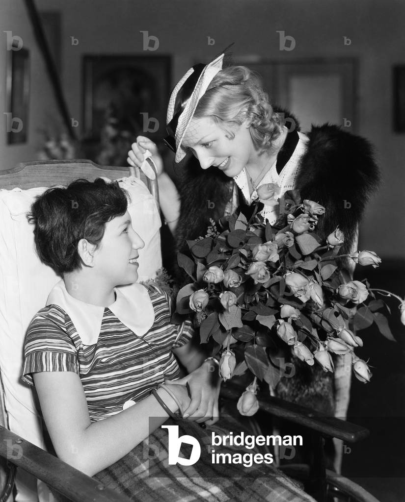Woman Giving Flowers to Girl in Wheelchair