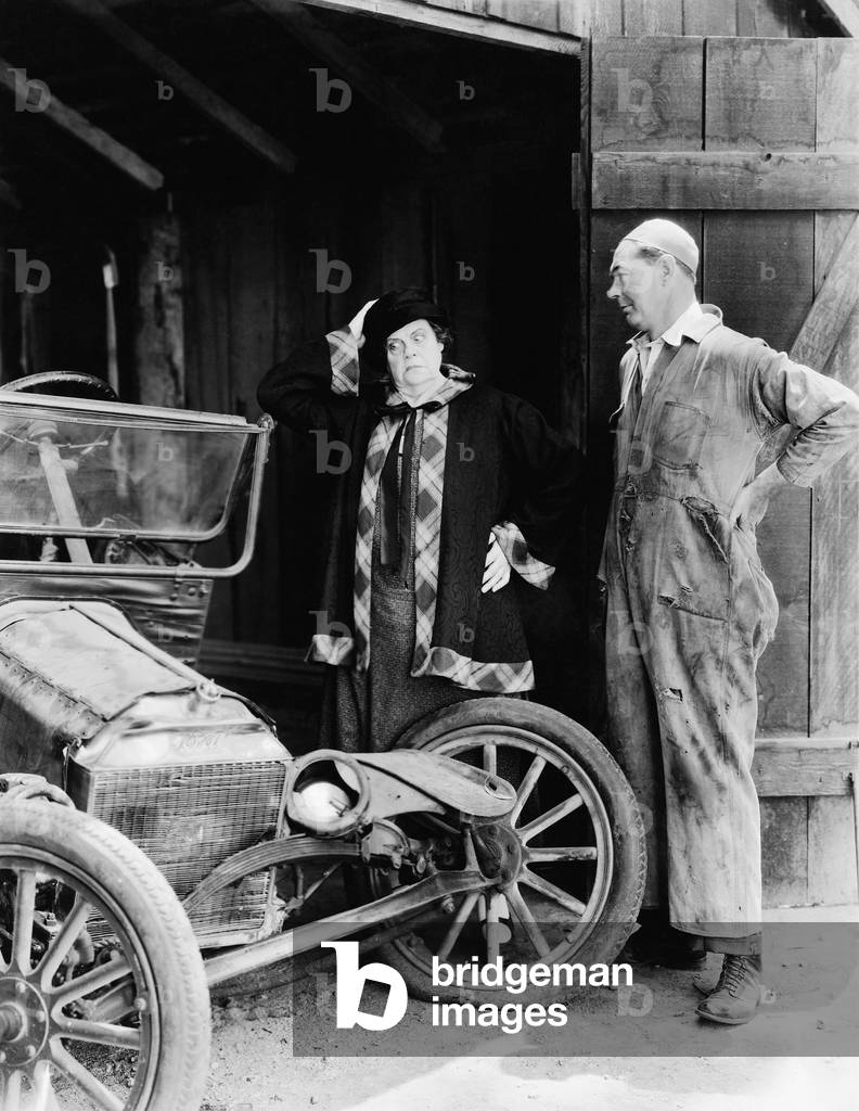 Man and Woman Looking at a Wrecked Car in the Barn