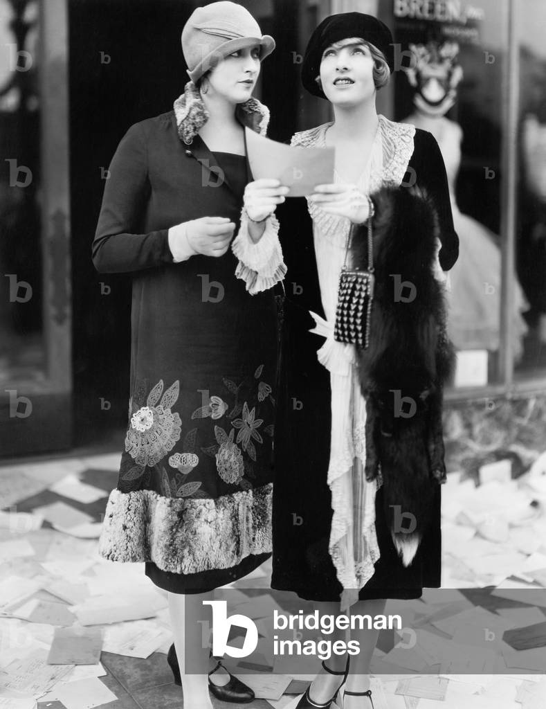 Two Women in the Street Reading Papers Being Thrown Down From an Office