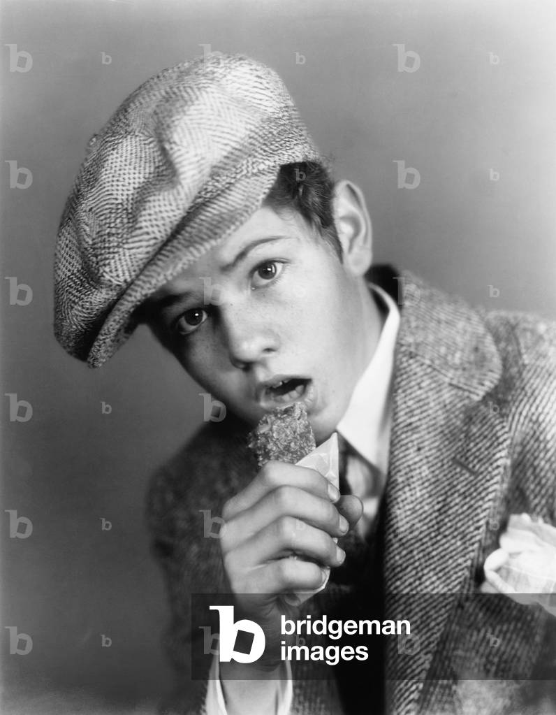Portrait of a Boy with a Hat Eating a Candy Bar