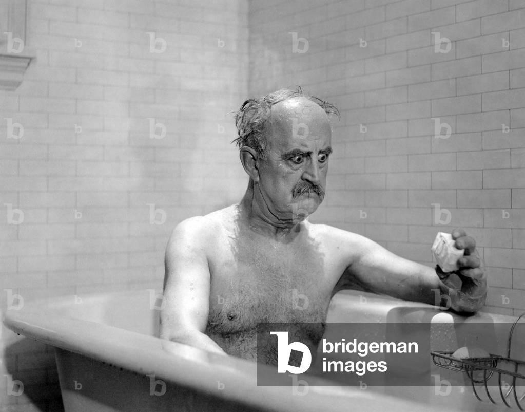 Man in bathtub glaring at soap