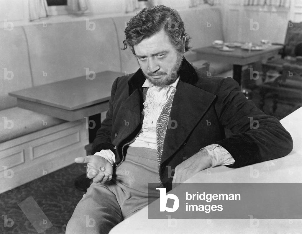 Man Leaning Against a Counter in a Restaurant with a Ring in his Hand Looking Sad
