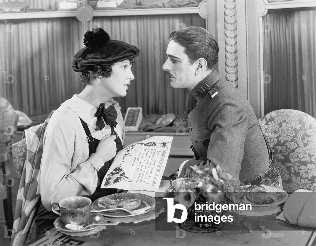Man in Uniform and a Woman Sitting Together at a Table and Looking at Each Other